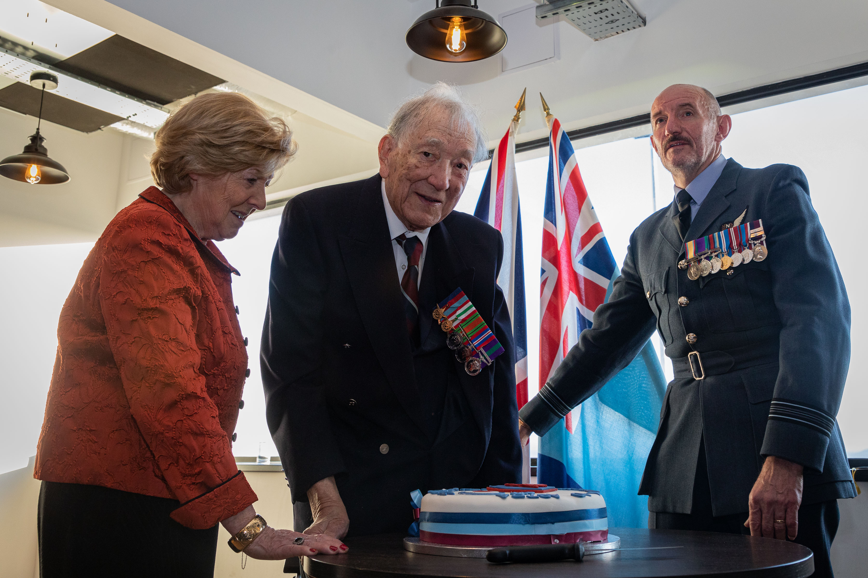 Image shows RAF aviators and veterans with birthday cake.